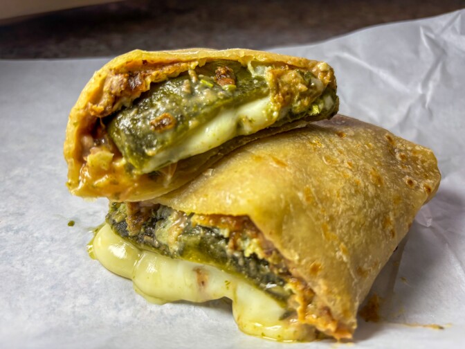 A molten cross-section of La Azteca’s iconic chile relleno burrito, where a roasted poblano pepper is inside a house-made flour tortilla.