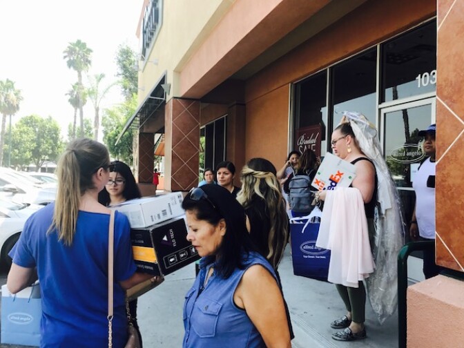 Alfred Angelo employees leave the store Friday morning, July 14, 2017, as crowds ask for help finding their bridal gowns.