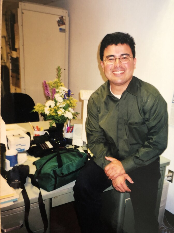 Person wearing glasses sits on a desk.