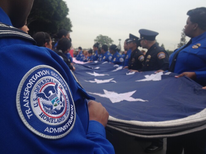A team of TSA officers and L.A. Airport Police officers fold a traveling honor flag that hung high above the entrance at the memorial held Tuesday for fallen TSA officer Gerardo Hernandez. 