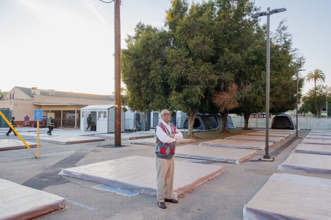 LA City Councilmember Curren Price, an African American man, stands in the middle of a safe-camping site surrounded by pallets that are meant for tents for unhoused people.