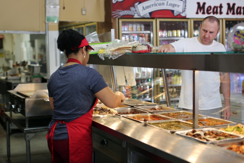 Poncitlan cook Enedina Arrellano makes a to-go order for a customer. Owner Irma Leticia Vega stopped selling groceries at the store because she couldn't compete on price. She decided to focus on authentic Mexican food, something Walmart and Super King don't have.