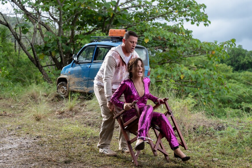 Sandra Bullock and Channing Tatum are present in a scene outdoors. Bullock sits in a chair with one chair leg snapping and she is about to fall. Tatum catches her.The movie is Paramount Pictures' "THE LOST CITY."