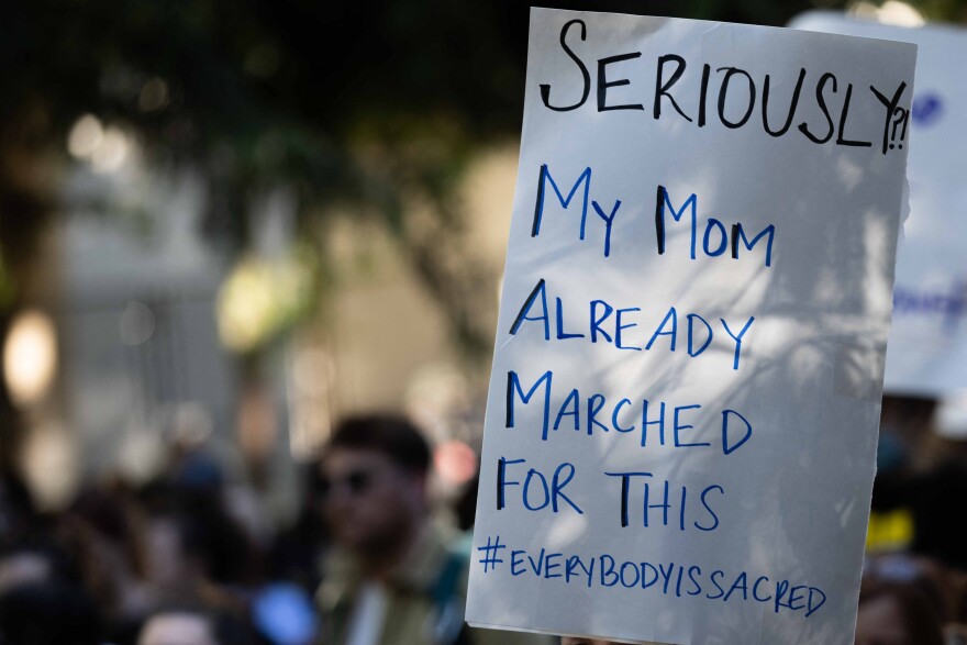 And abortion rights activists sign reads: "Seriously my mom already marched for this #everybodyissacred"