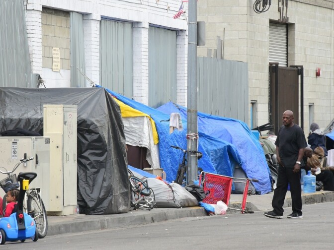A man walks beside a row of tents for the homeless in Los Angeles, California on May 12, 2015.