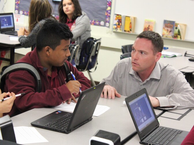 Andrew Osterhaus, a science teacher at Animo Florence-Firestone Middle School, a charter school in South L.A., assists a student as he works on a worksheet.