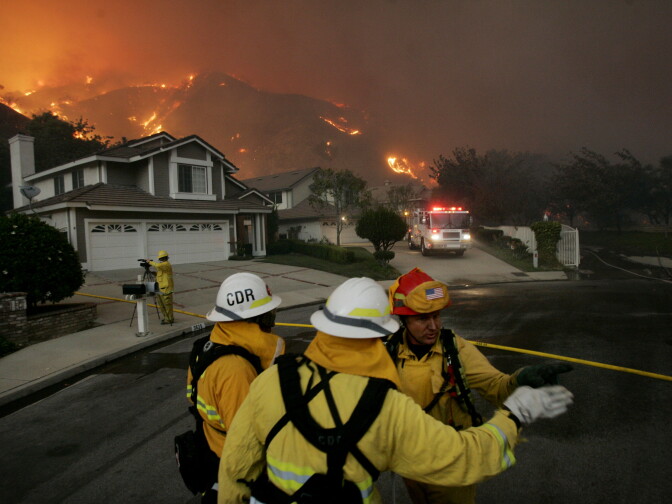 YORBA LINDA, CA - NOVEMBER 15:  Firefighters battle a blaze November 15, 2008 in Yorba Linda, California. Strong Santa Ana winds are fanning flames throughout Southern California, destroying hundreds of homes and causing thousands to evacuate. (Photo by Sandy Huffaker/Getty Images)