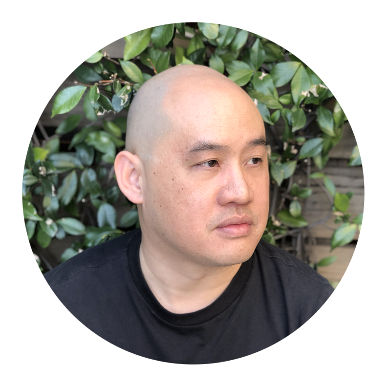 A portrait of a Taiwanese American man in a black t-shirt gazing off to the side.