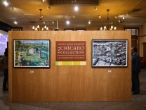 Two paintings - one colorful, one black and white - are shown on a wall. In the center, a plaque that reads "Cheech Marin presents The Chicano Collection/La Colección Chicana."