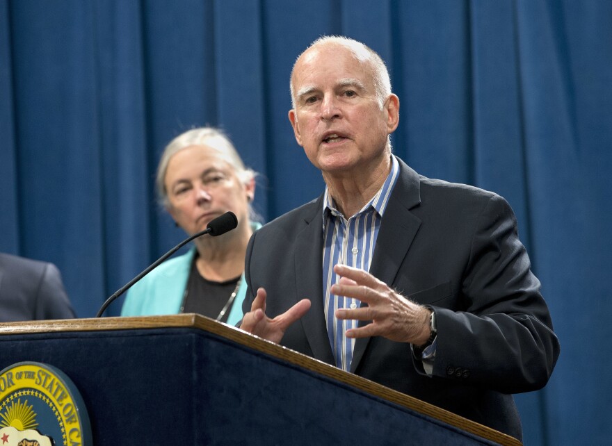 Calif. Gov. Jerry Brown discusses the passage of a measure for a 10-year extension of the state's landmark climate change law during a news conference, Wednesday, Aug. 24, 2016, in Sacramento, Calif. Brown said he would sign SB32, by Sen Fran Pavley, D-Agoura Hills, left, that sets a new goal to reduce greenhouse gas emissions to 40 percent below 1990 levels by 2030. 