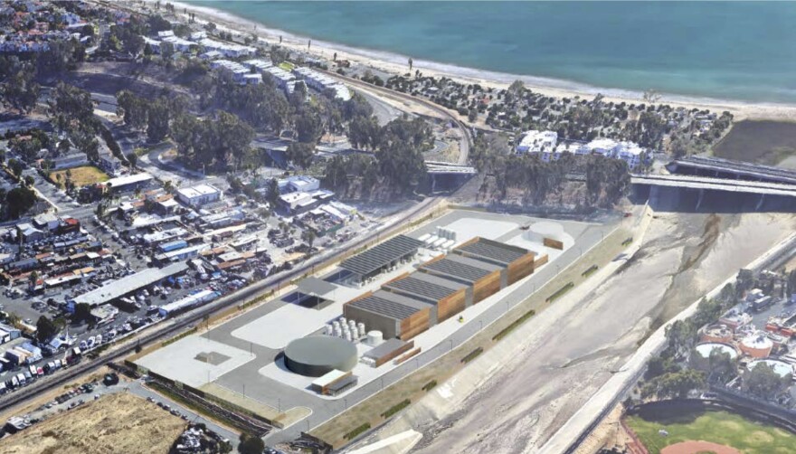 An artistic rendering of a proposed ocean desalination plant in Dana Point, CA, seen from an overhead perspective. The plant with several buildings can be seen in the foreground and in the distance is a beach and the ocean .