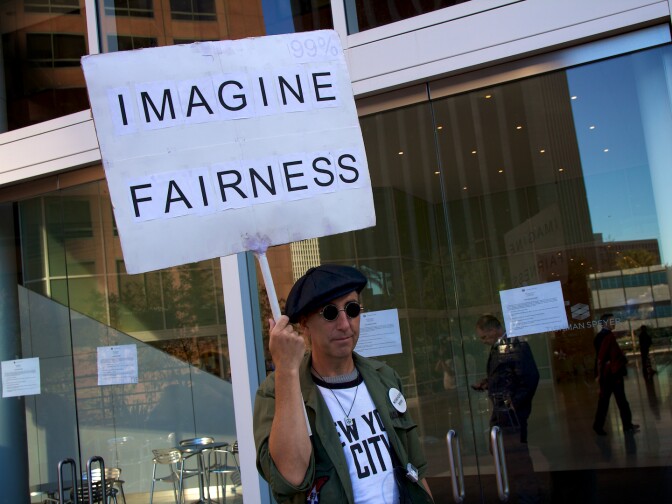 An Occupy LA supporter dressed as John Lennon marches outside the BNY Mellon Bank during today's protest.