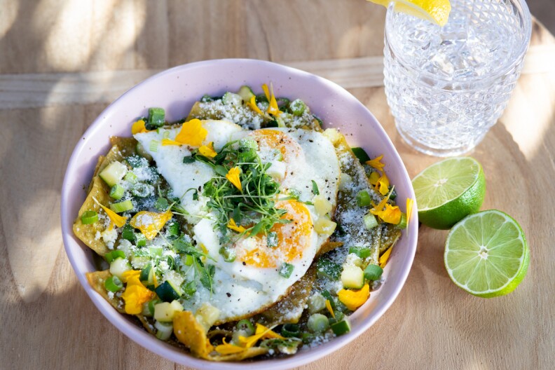 A plant-based dish with a cut lime and a glass of water on the side.