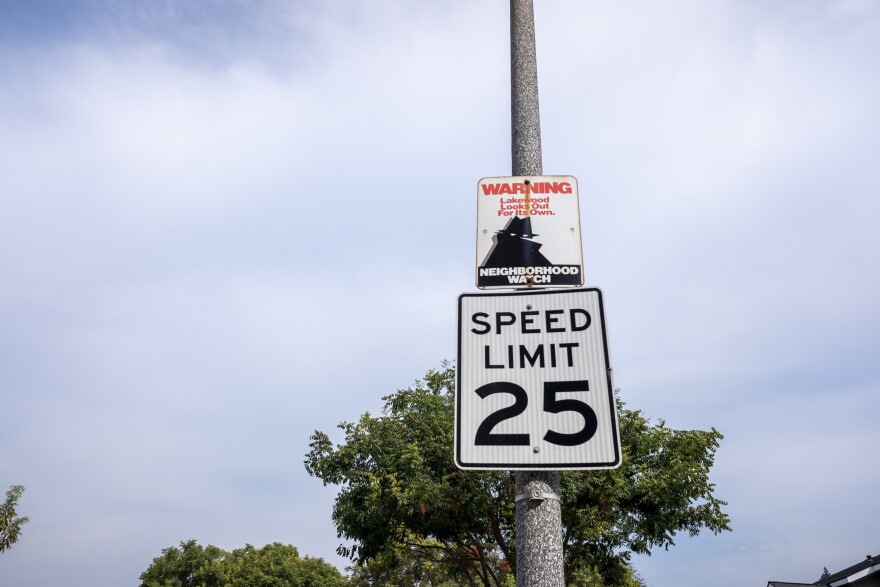 A 25 miles per hour speed limit sign is shown tacked to a pole, with a neighborhood watch sign above it.