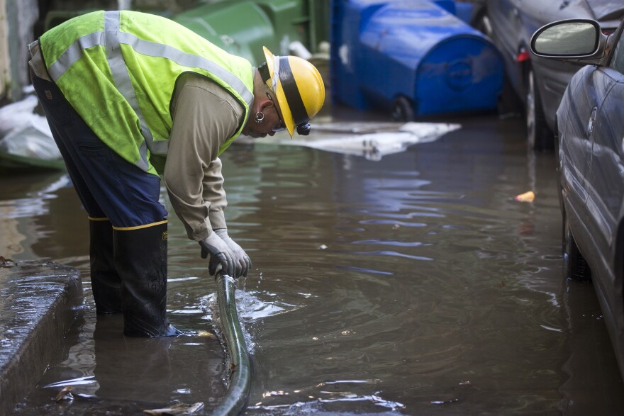 Chad Newlee, a line patrol mechanic for Los Angeles Department of Water and Power, works to pump water out of the back of an apartment building in order to check electric panels after an 18-inch main burst in Hollywood early Wednesday morning, Feb. 18, 2015 releasing a torrent of water onto residential streets and submerging cars.