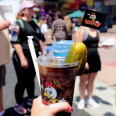 A "Chicken Charlie's" Dr. Pepper is held up in front of a crowd of OC Fair people.