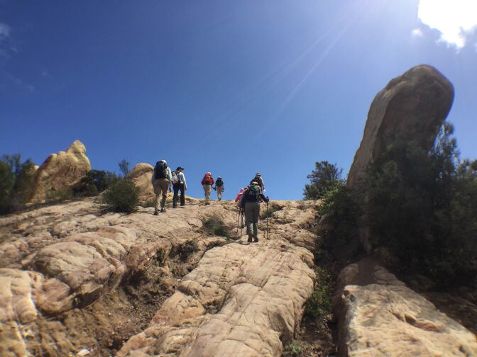 Hikers make their way along sandstone rock formations east of Corral Canyon Road.