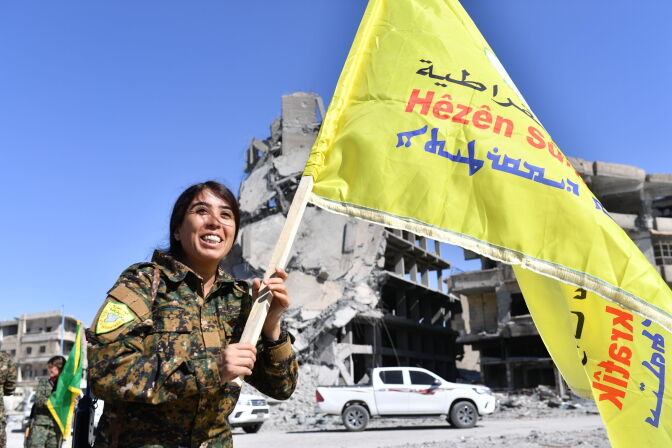 Rojda Felat, a Syrian Democratic Forces (SDF) commander, walks with her group's flag at the iconic Al-Naim square in Raqa on October 17, 2017.
US-backed forces said they had taken full control of Raqa from the Islamic State group, defeating the last jihadist holdouts in the de facto Syrian capital of their now-shattered "caliphate". / AFP PHOTO / BULENT KILIC        (Photo credit should read BULENT KILIC/AFP/Getty Images)