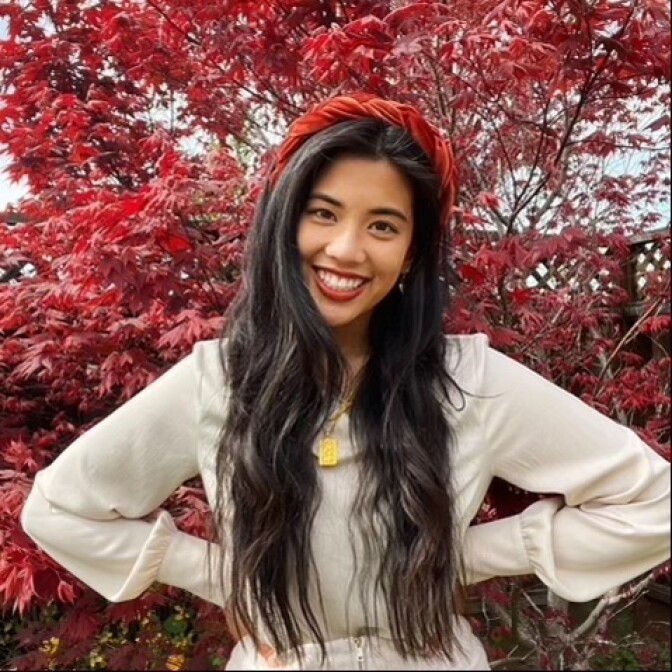 Photo of long-haired, smiling Taiwanese American woman with her arms akimbo