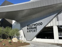 A wide view of the new Hollywood Burbank Airport sign that's connected to a large rounded overhang across the facility. 