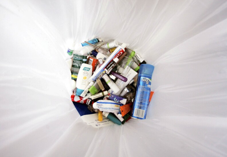 Liquids and gel containers in a white trash bag.