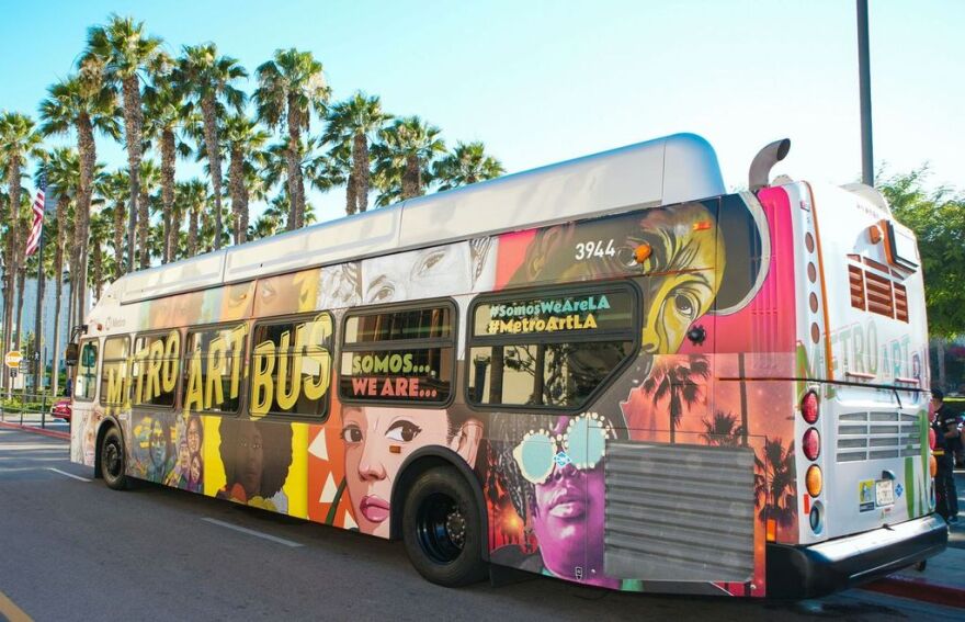 The exterior of a Metro bus covered with a colorful collage of portraits in different art styles.