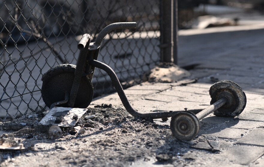 A close up of a burned tricycle with piles of ash around it.