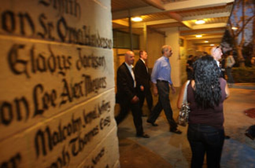 U.S. Attorney General Eric Holder passes memorial murals upon which are written hundreds of names of people killed by gang violence at the Nickerson Gardens Recreation Center after meeting with community youth and families participating in the Los Angeles anti-gang program, Summer Night Lights, and the Watts Gang Task Force on July 16, 2009 in South Los Angeles, California.