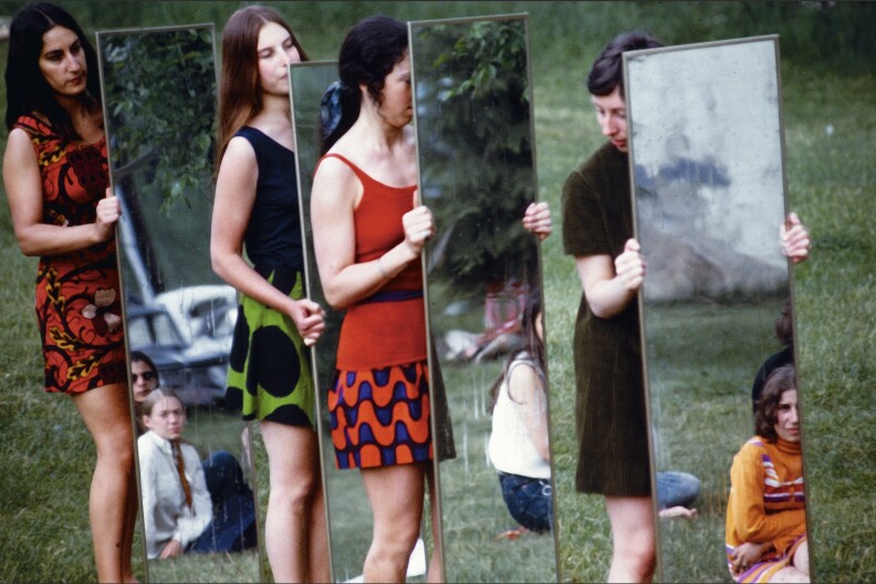 Four women holding up body length mirrors