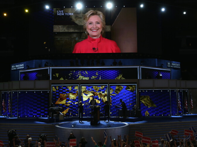 Delegates cheer as a screen displays Democratic presidential candidate Hillary Clinton delivering remarks to the crowd during the evening session on the second day of the Democratic National Convention at the Wells Fargo Center, July 26, 2016 in Philadelphia, Pennsylvania. 