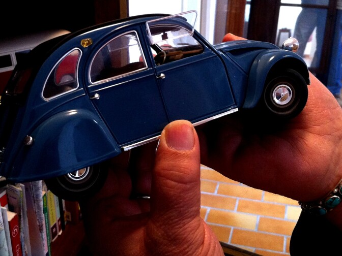 In LA, Frank Romero paints low riders and other quintessential LA cars; in France, he turns to the famous French models, and collects photos, ads, and models of cars, like this one.