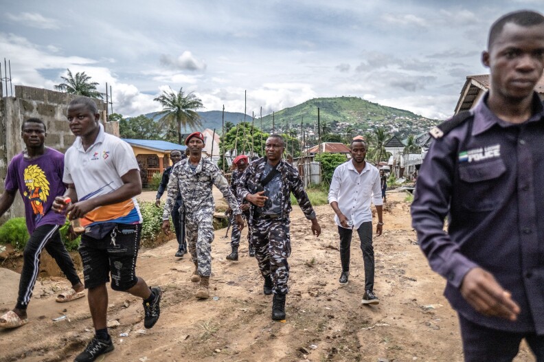 A combined military and police task force, including some in plain clothes, return to their vehicles after arresting a suspected kush dealer in Waterloo, Sierra Leone.