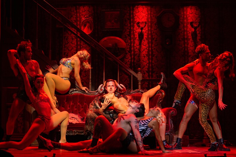 The ensemble of "Reefer Madness" onstage during a provocative number. Cast members are wearing tight leopard print leggings and swimsuits while holding dance poses.