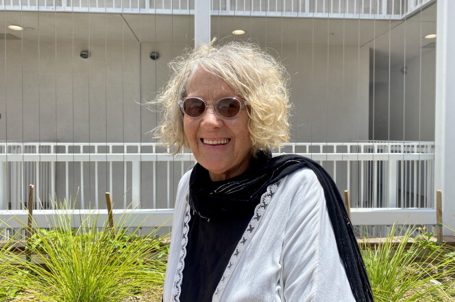 Sumaiyya Evans is photographed in the courtyard of her apartment building. She's wearing sunglasses and a black shirt with a white shawl.