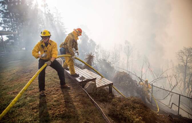 Firefighters work to save burning houses along Linda Flora Drive during the Skirball Fire in Los Angeles, California, December 6, 2017.
The "Skirball" fire ignited before 5 a.m. (1300 GMT) and quickly engulfed some 50 acres, with forecasters predicting the 25-mile-per-hour winds could cause further spreading, threatening multi-million dollar homes and the acclaimed Getty Center museum. / AFP PHOTO / Kyle Grillot        (Photo credit should read KYLE GRILLOT/AFP/Getty Images)