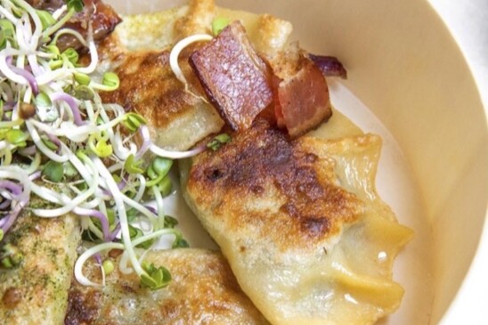A crispy pierogi topped with bacon and garnishes.