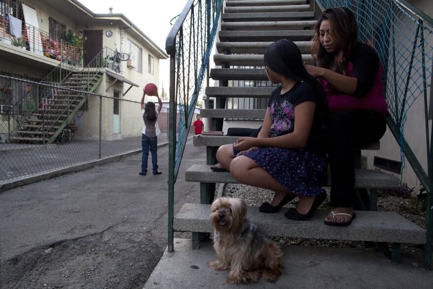 Claudia Chi Ku braids the hair of her daughter, Leslie Soriano, 11, as her other children play outside of their apartment in Pico Union. Chi Ku supports her family while working as a cashier at a restaurant in the neighborhood.