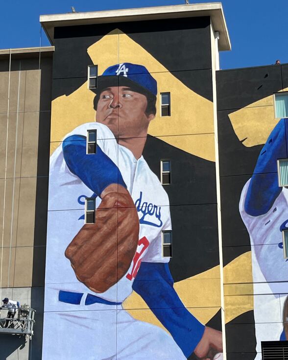 A giant mural on a wall of a baseball pitcher.