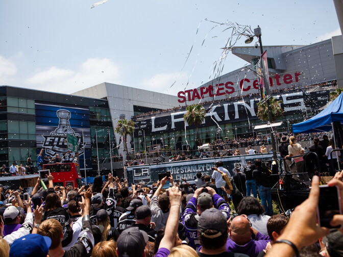 Fans erupt in applause as LA Kings captain, Dustin Brown, holds the Stanley Cup over his head during the team's celebratory parade.