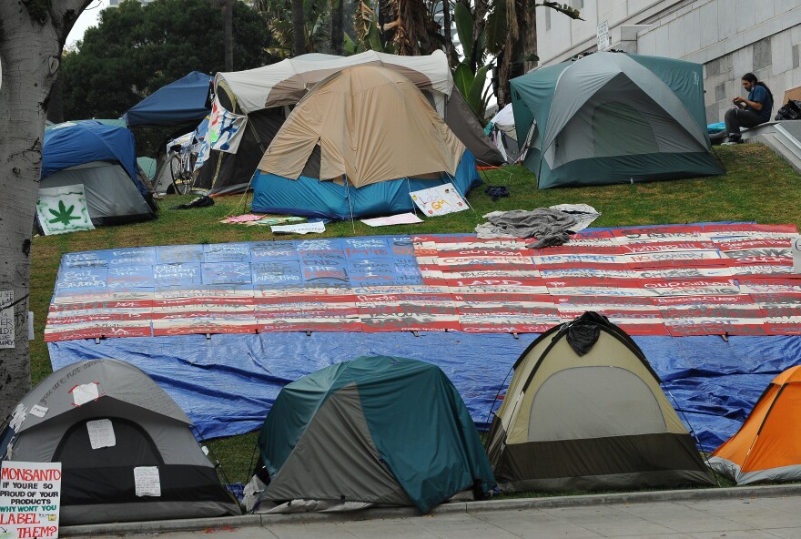 A demonstrator sits outside a tent at the Occupy LA encampment in front of Los Angeles City Hall October 25, 2011.  Demonstrators at the encampment are protesting bank bailouts, foreclosures and high unemployment. 