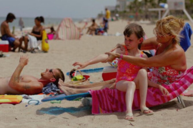 Sharon Doyle puts sunscreen on the arm of 9-year-old Savannah Stidham as they visit the beach