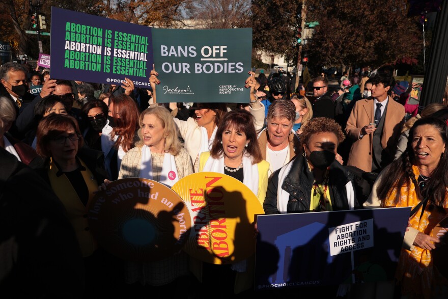 An abortion rights protest. A large group of mostly women chant and hold signs reading "bans off our bodies" and "abortion is essential."