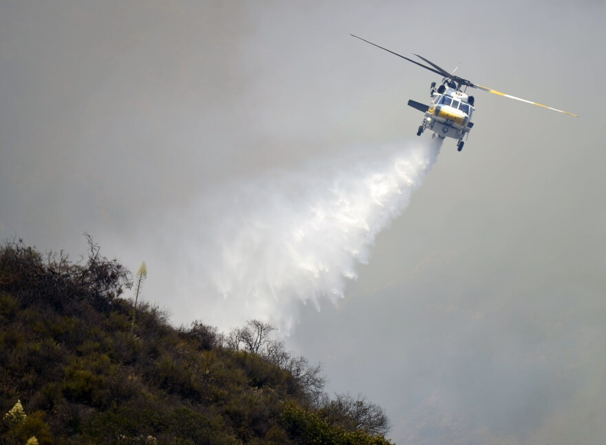 A Los Angeles County Fire Department helicopter makes a water drop on the Brand Fire Sunday afternoon. 