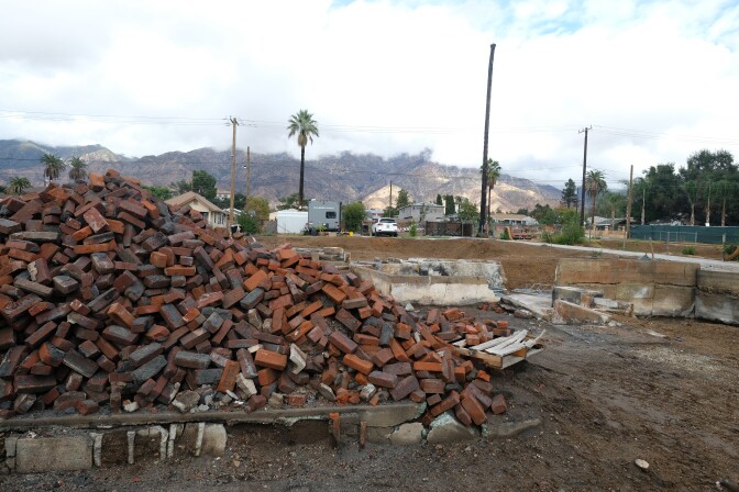 A large pile of bricks on a dirt lot under overcast skies. 