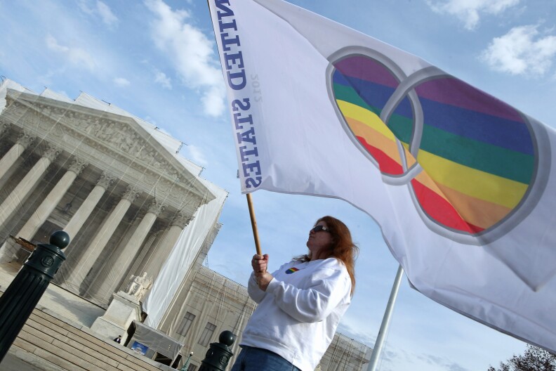 Same-sex marriage proponent Kat McGuckin of Oaklyn, New Jersey, holds a gay marriage pride flag while standing in front of the Supreme Court November 30, 2012 in Washington, DC. With the Supreme Court building draped in a photo-realistic sheet during a repair and preservation project, the justices met today to consider hearing several cases dealing with the rights of gay couples who are married, want to get married or are in domestic partnerships.