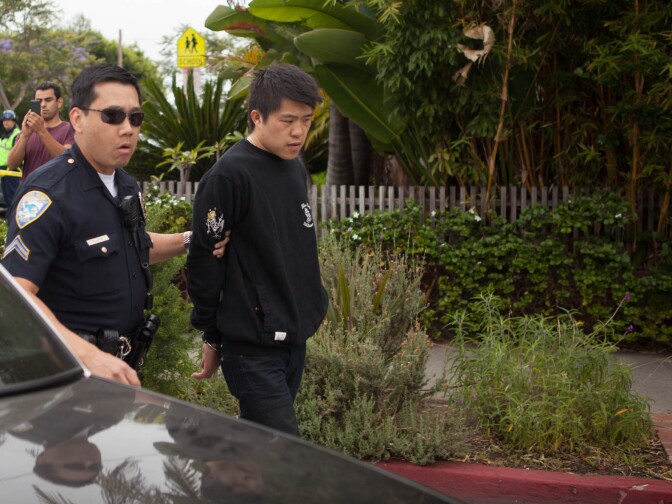 A man who gave his name as Michael Lim is taken to a police car in handcuffs near Santa Monica College on Friday.