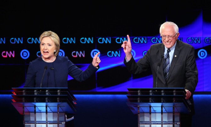 FLINT, MI - MARCH 06:  Democratic presidential candidate Senator Bernie Sanders (D-VT) and Democratic presidential candidate Hillary Clinton speak during the CNN Democratic Presidential Primary Debate at the Whiting Auditorium at the Cultural Center Campus on March 6, 2016 in Flint, Michigan. Voters in Michigan will go to the polls March 8 for the state's primary.  (Photo by Scott Olson/Getty Images)