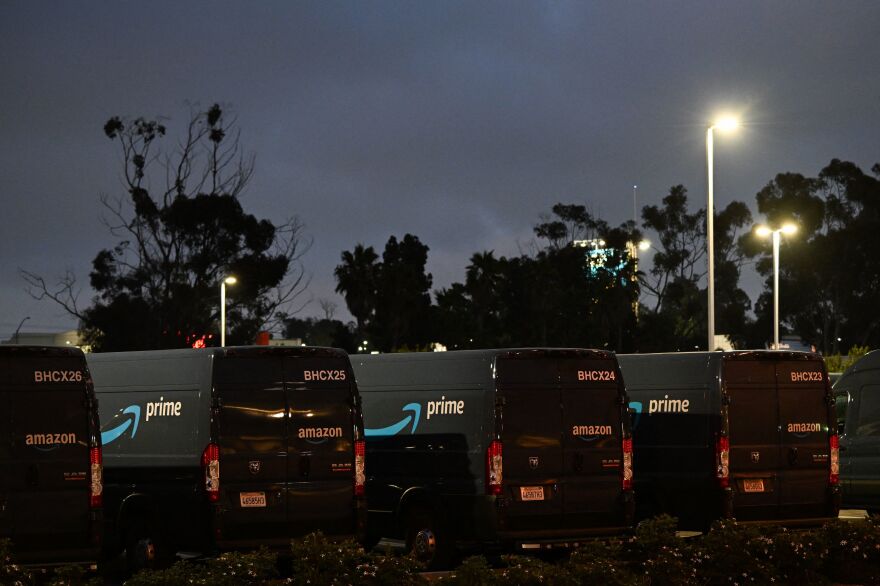 Amazon Prime delivery vans sit under street lights.