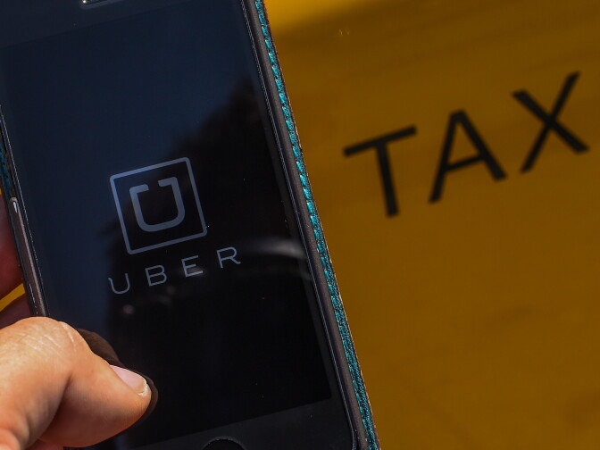 BARCELONA, SPAIN - JULY 01:  In this photo illustration, the new smart phone app 'Uber' logo is displayed on a mobile phone next to a taxi on July 1, 2014 in Barcelona, Spain. Taxi drivers in main cities strike over unlicensed car-halling services. Drivers say that is a lack of regulation behind the new app.  (Photo Illustration by David Ramos/Getty Images)