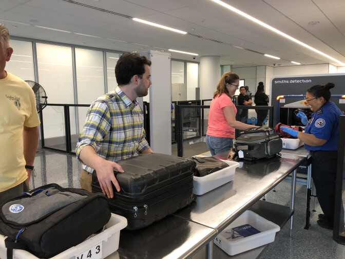 Passengers prepare their carry-on luggage for the new 3D scanner.